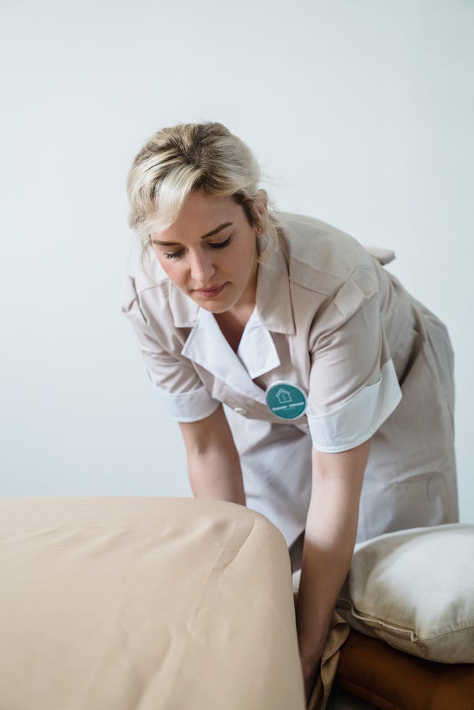 A dedicated housekeeper making a bed, showcasing professionalism and attention to detail.