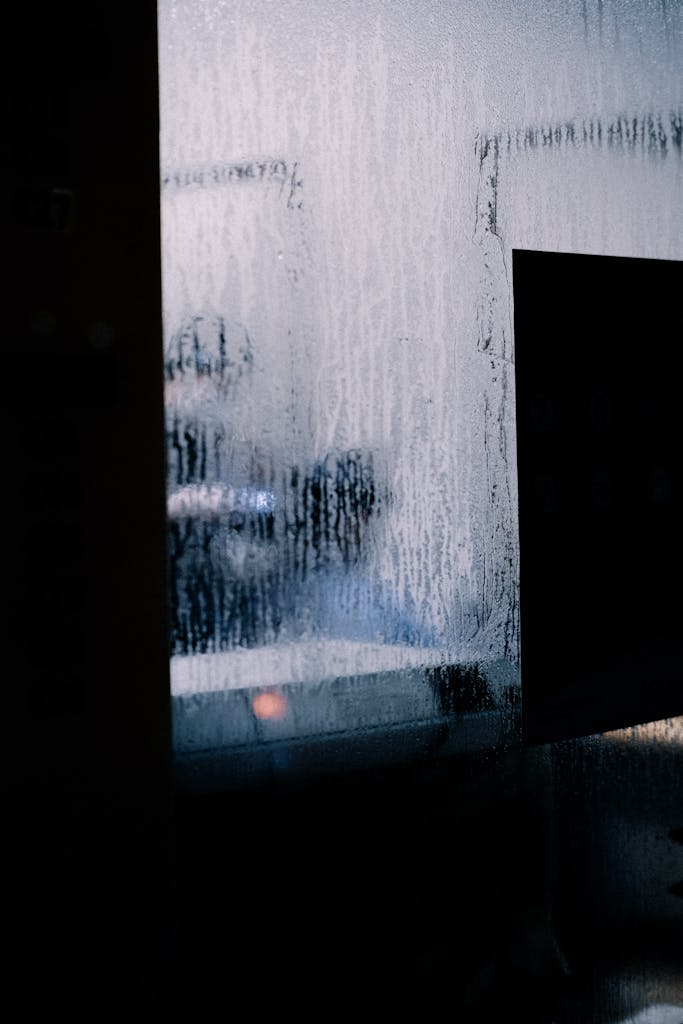 Blurred silhouette through a moist window capturing a mysterious and artistic scene.