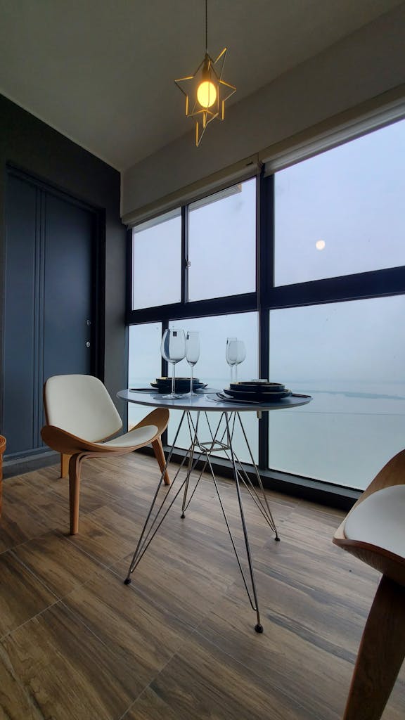 Contemporary dining setup with chairs, table, and ocean view from a window.