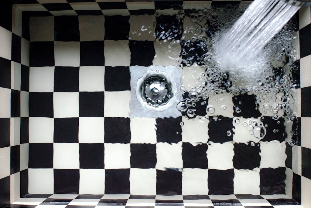 Top view of a checkered sink with water splashing, showcasing elegant design.